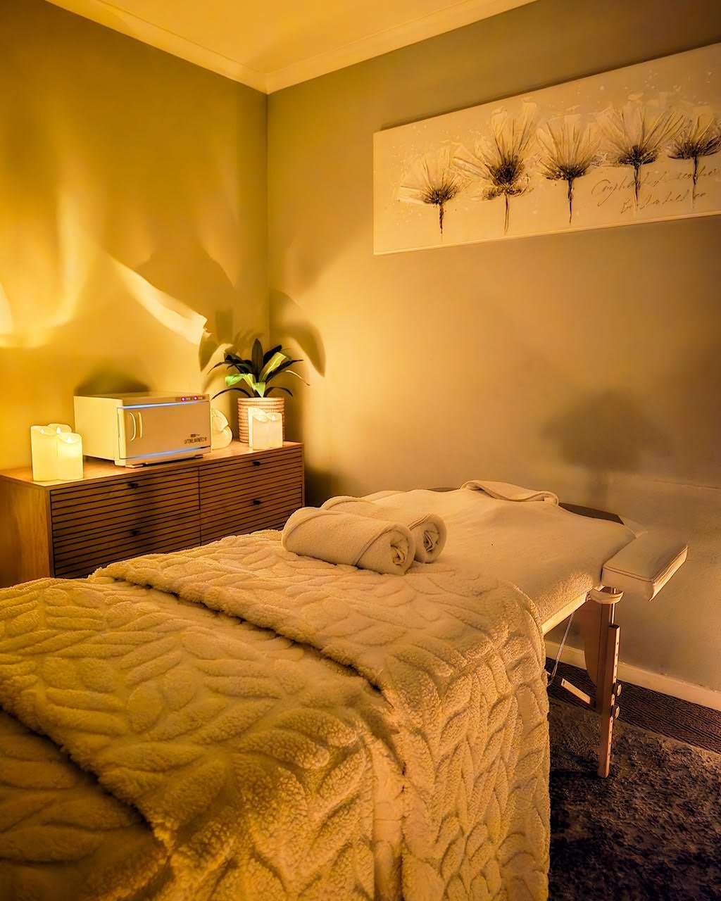 A treatment room at Nirvana Nook Wellness Spa, softly lit with a massage bed, warm towels, and candles