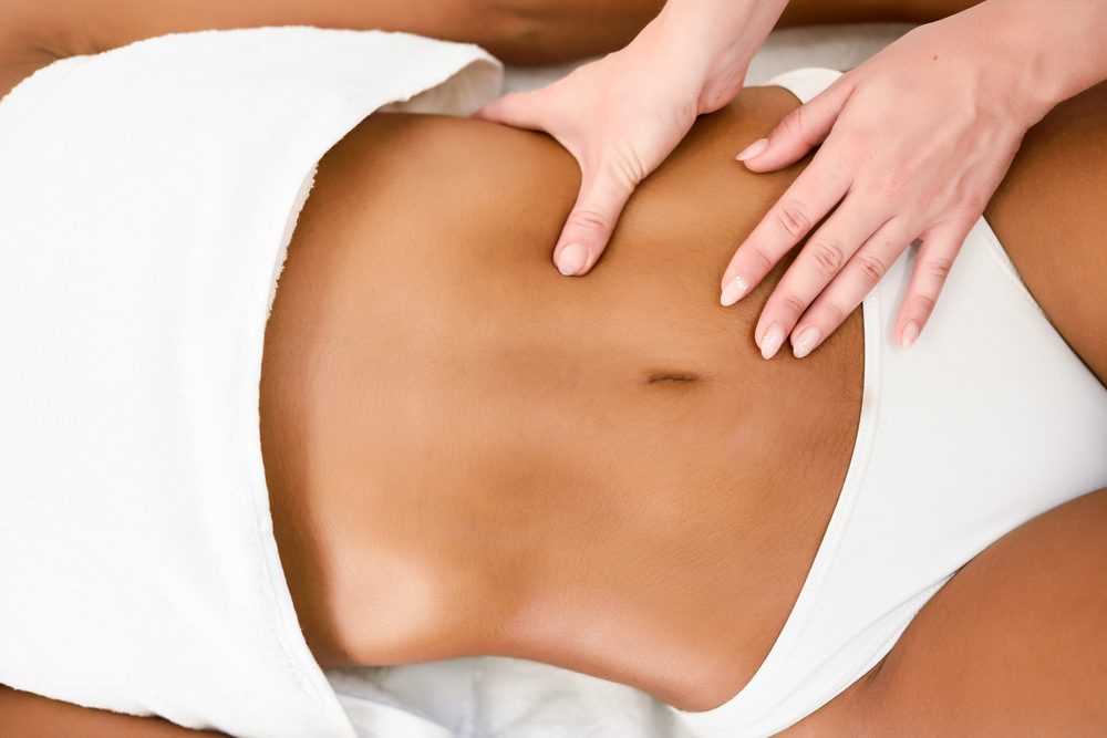 Therapist performing a gentle lymphatic stomach massage on a guest's abdomen
